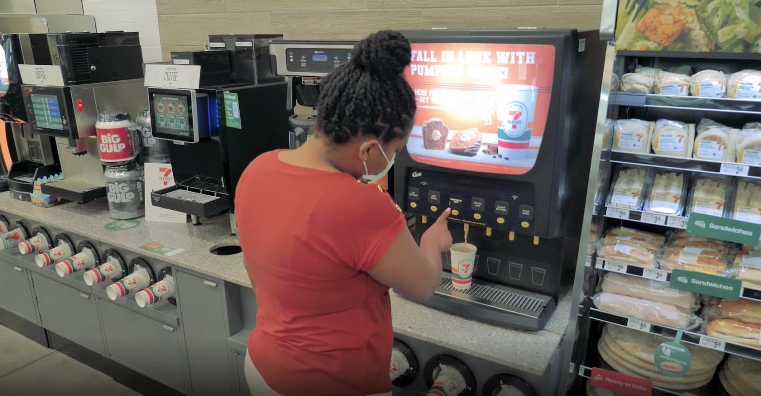 Woman Pouring a Beverage at a c-store self-service station and wrapped sandwiches nearby