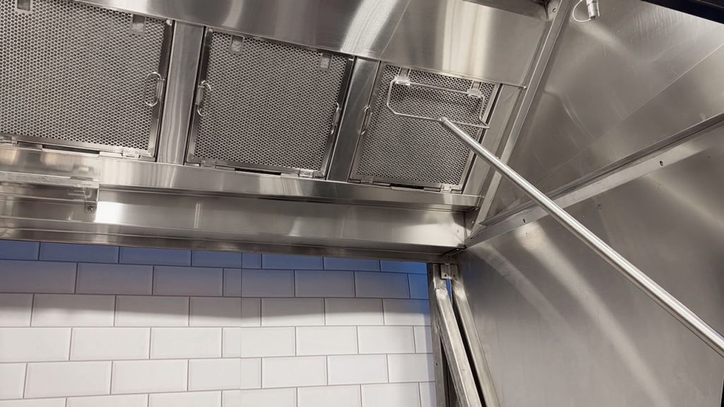 A tool is used to remove one of a row of Franke cascade filters from a canopy exhaust hood