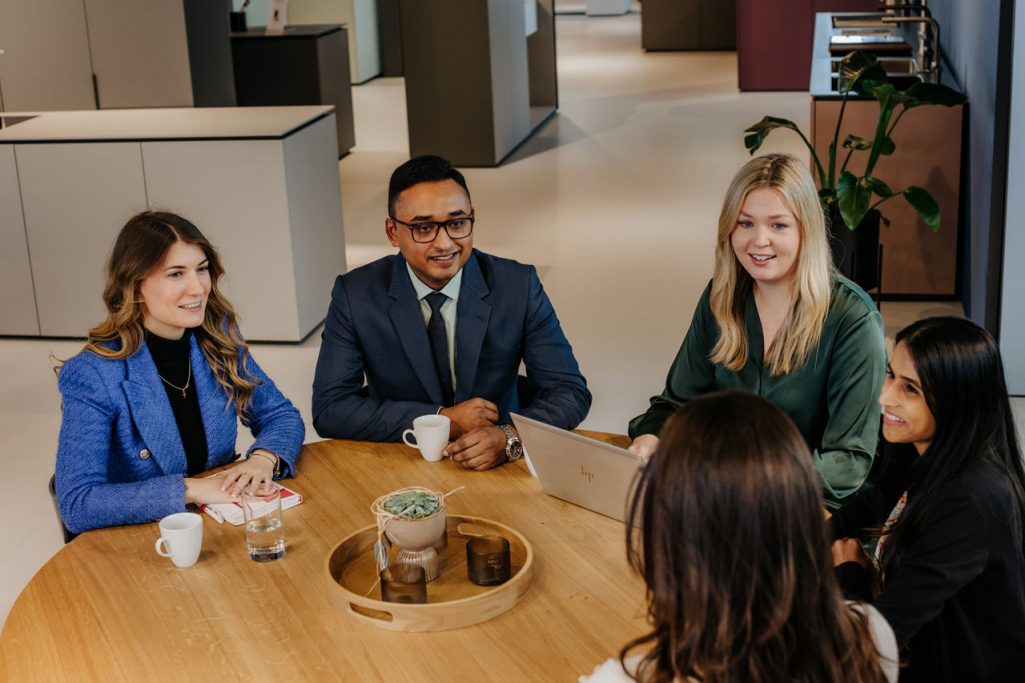 group of six young people standing around a table working