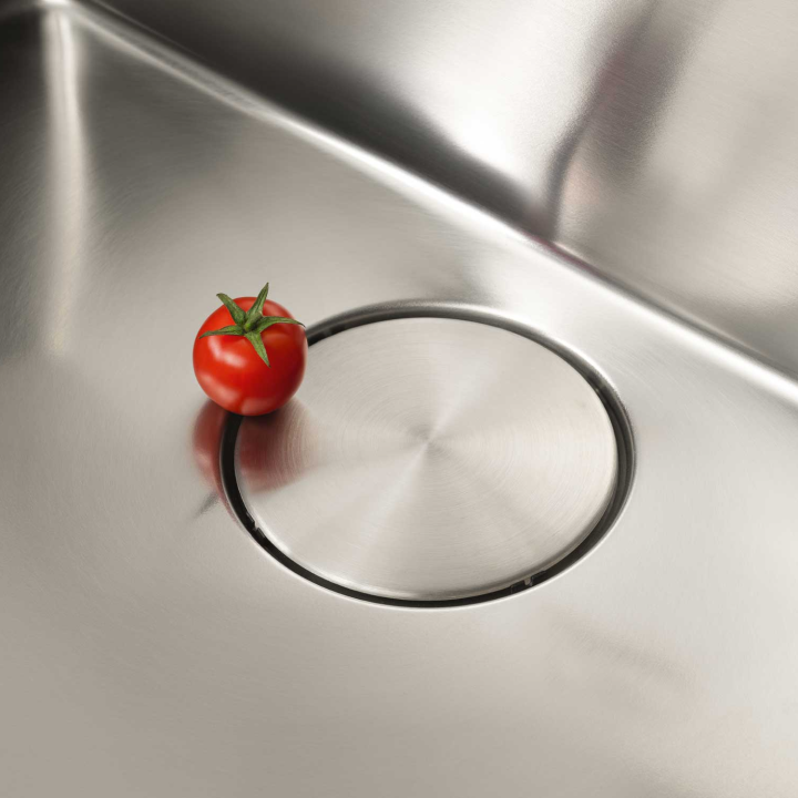Tomato in a kitchen sink next to the drain cover